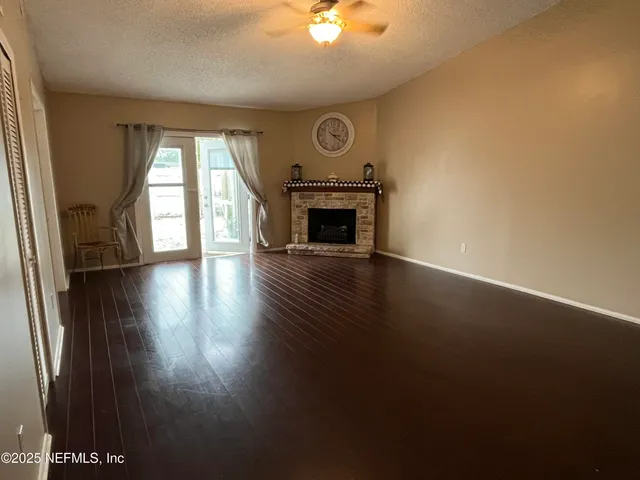 an empty room with wooden floor fan and windows