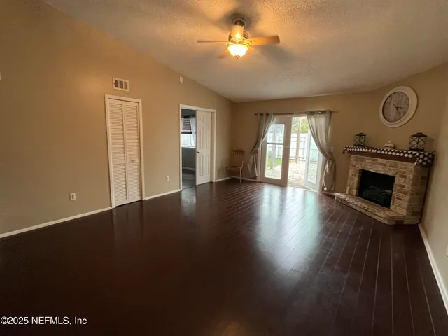 an empty room with windows fireplace and wooden floor