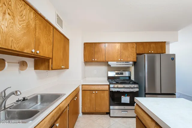 a kitchen with stainless steel appliances a stove a refrigerator and a sink