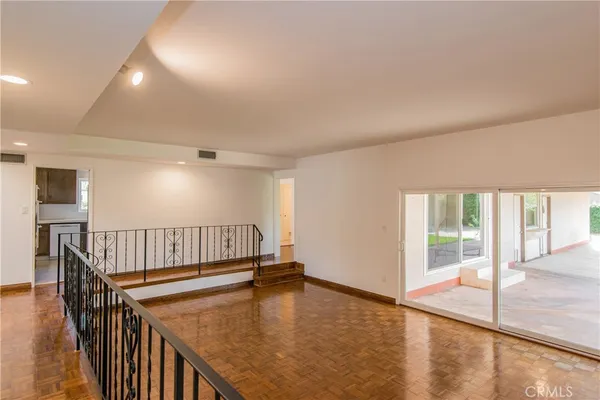 an empty room with wooden floor windows and a ceiling fan