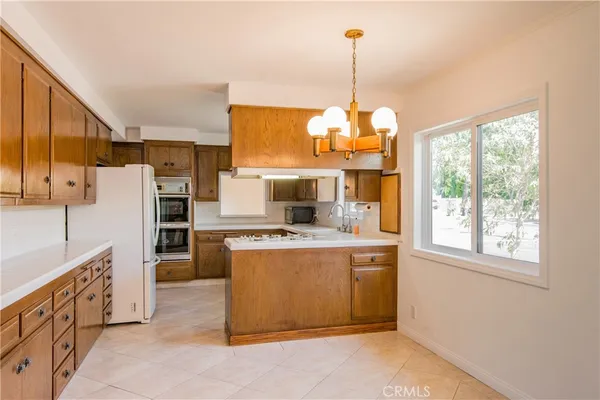 a kitchen with stainless steel appliances granite countertop a stove a refrigerator a oven and a sink with large windows