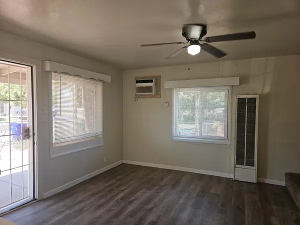 a view of an empty room with wooden floor and a window