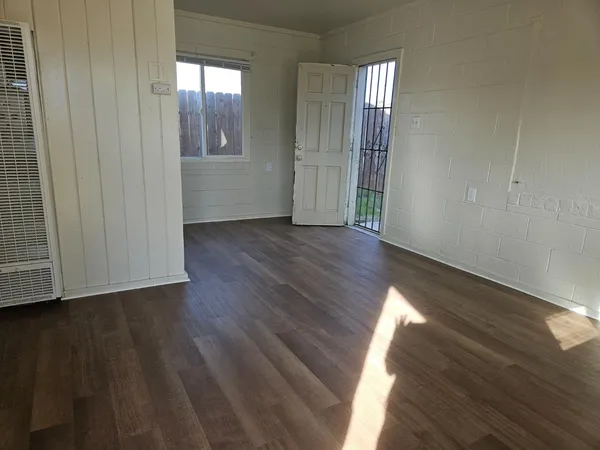 an empty room with wooden floor and windows