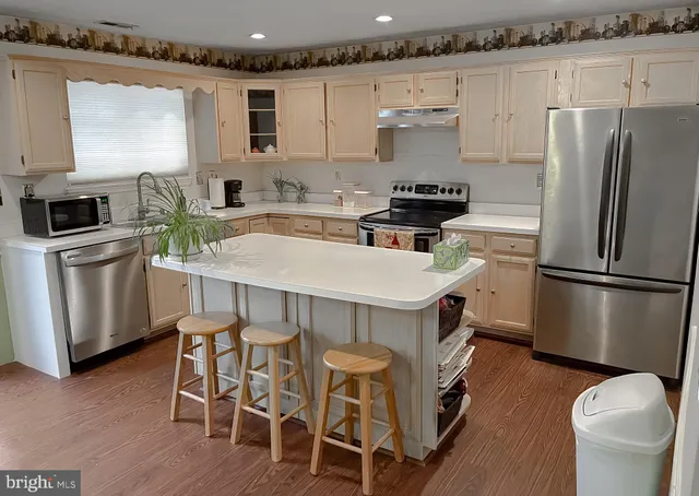 a kitchen with stainless steel appliances a stove a sink a microwave a refrigerator and white cabinets