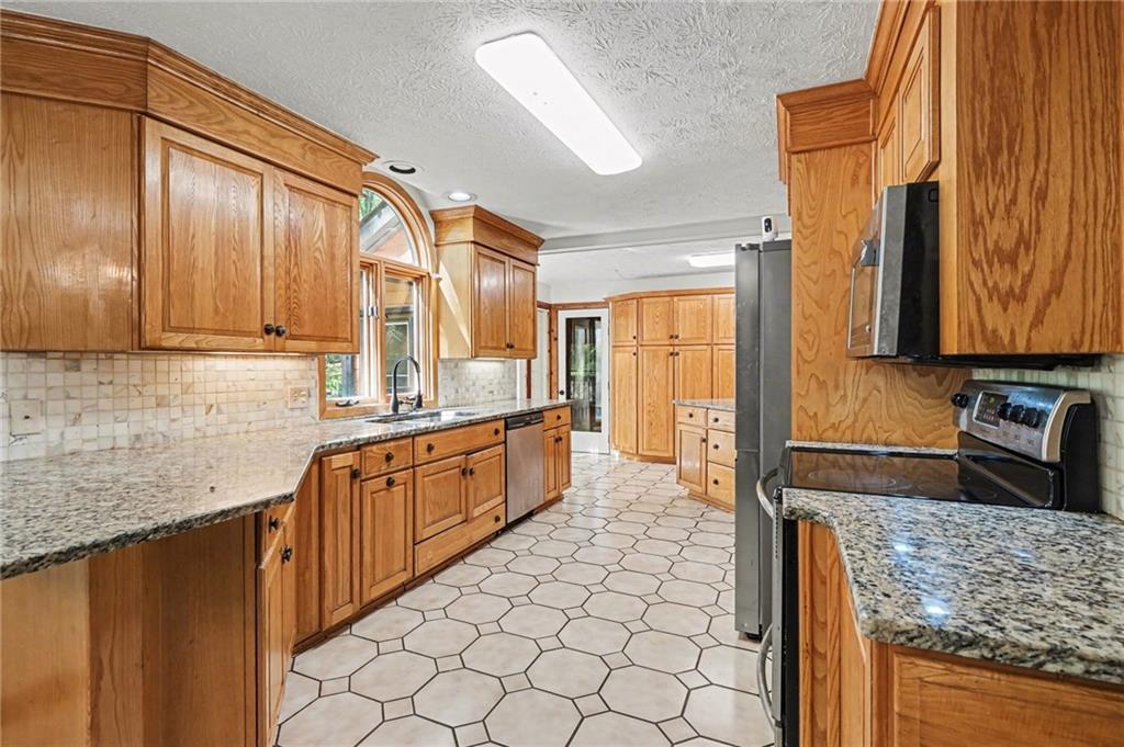 2530 Rockbridge Road Northwest Conyers, GA 30012 - Photo 10 of 45 a large kitchen with granite countertop a sink and dishwasher a stove top oven with wooden floor