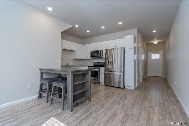 a kitchen with kitchen island wooden floors appliances and cabinets