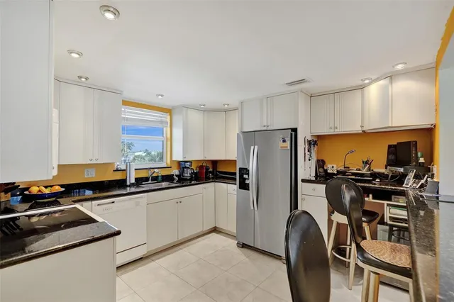 a kitchen with stainless steel appliances a refrigerator a sink a stove a table and chairs