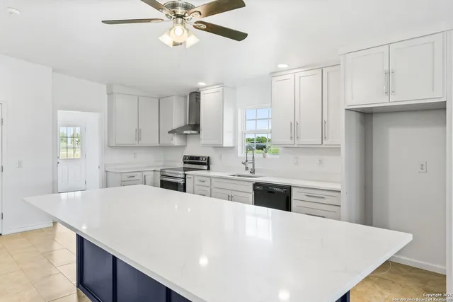 a kitchen with stainless steel appliances a stove a sink dishwasher a refrigerator white cabinets and wooden floor
