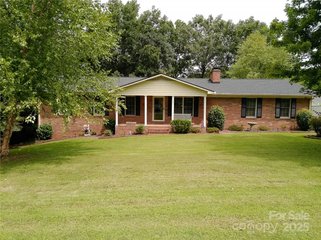 a front view of a house with a garden and trees