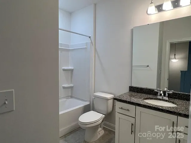 a bathroom with a granite countertop toilet a sink and a mirror
