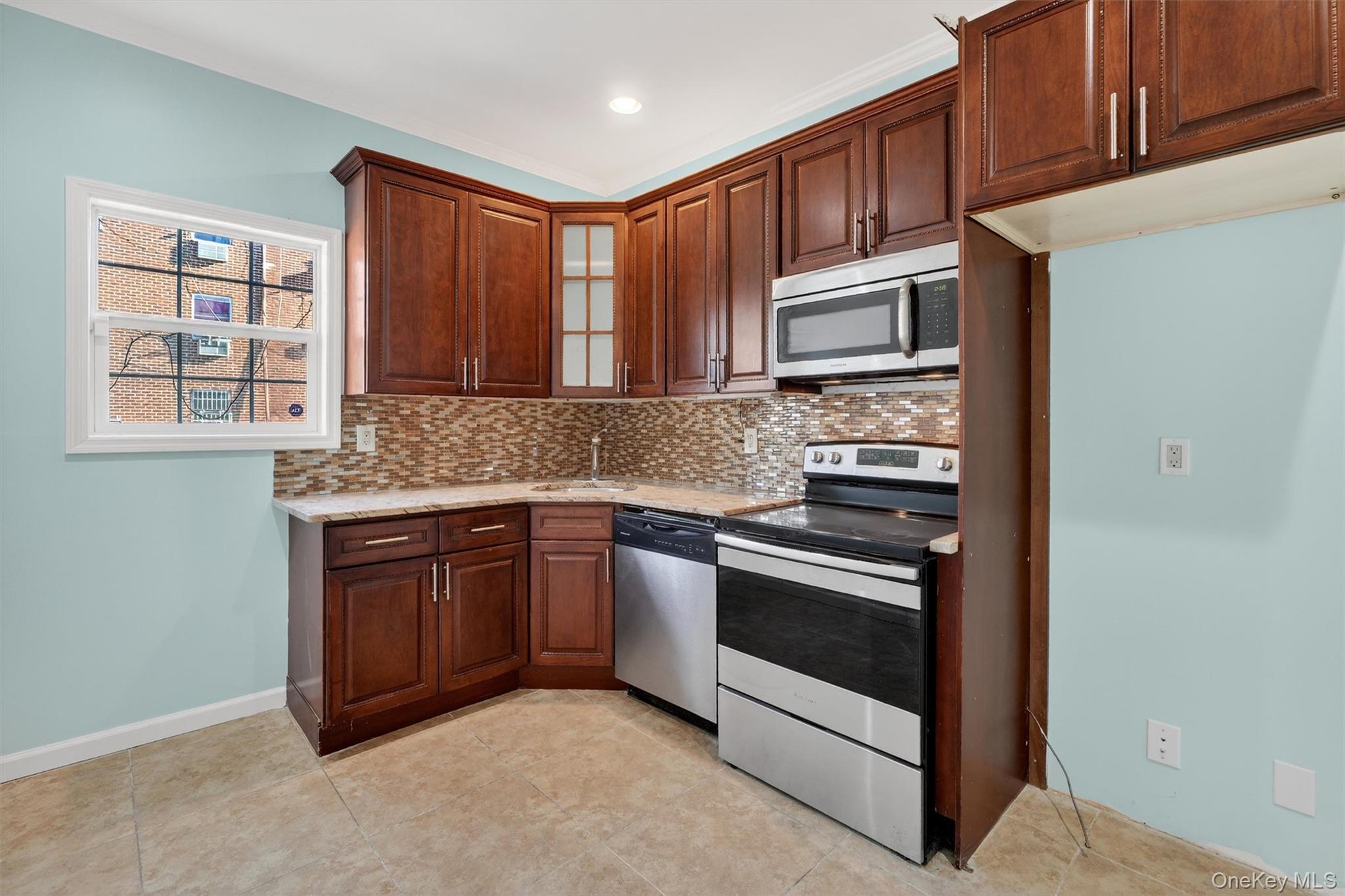 636 Throgs Neck Expressway Bronx, NY 10465 - Photo 12 of 31 Kitchen with stainless steel appliances, backsplash, glass insert cabinets, light stone countertops, and ornamental molding