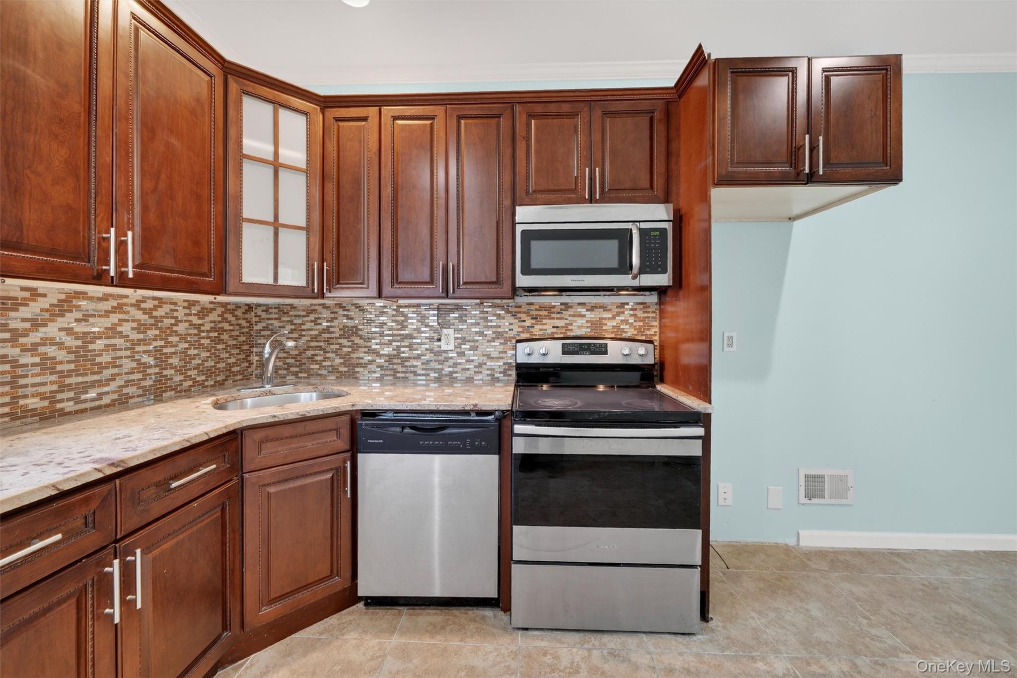 636 Throgs Neck Expressway Bronx, NY 10465 - Photo 16 of 31 Kitchen with stainless steel appliances, light stone countertops, glass insert cabinets, light tile patterned floors, and decorative backsplash
