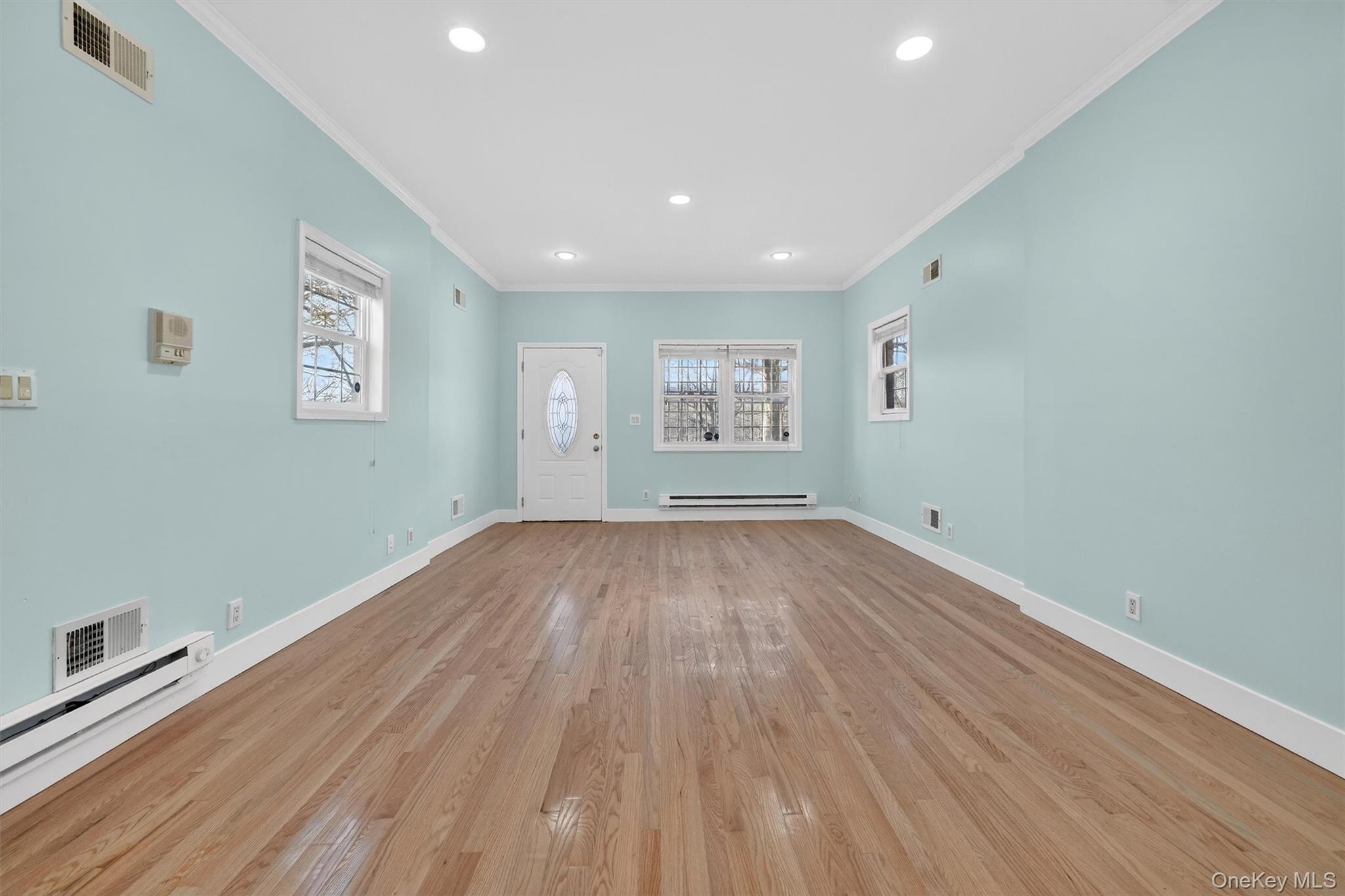 636 Throgs Neck Expressway Bronx, NY 10465 - Photo 7 of 31 Unfurnished living room featuring ornamental molding, recessed lighting, wood finished floors, healthy amount of natural light, and a baseboard heating unit