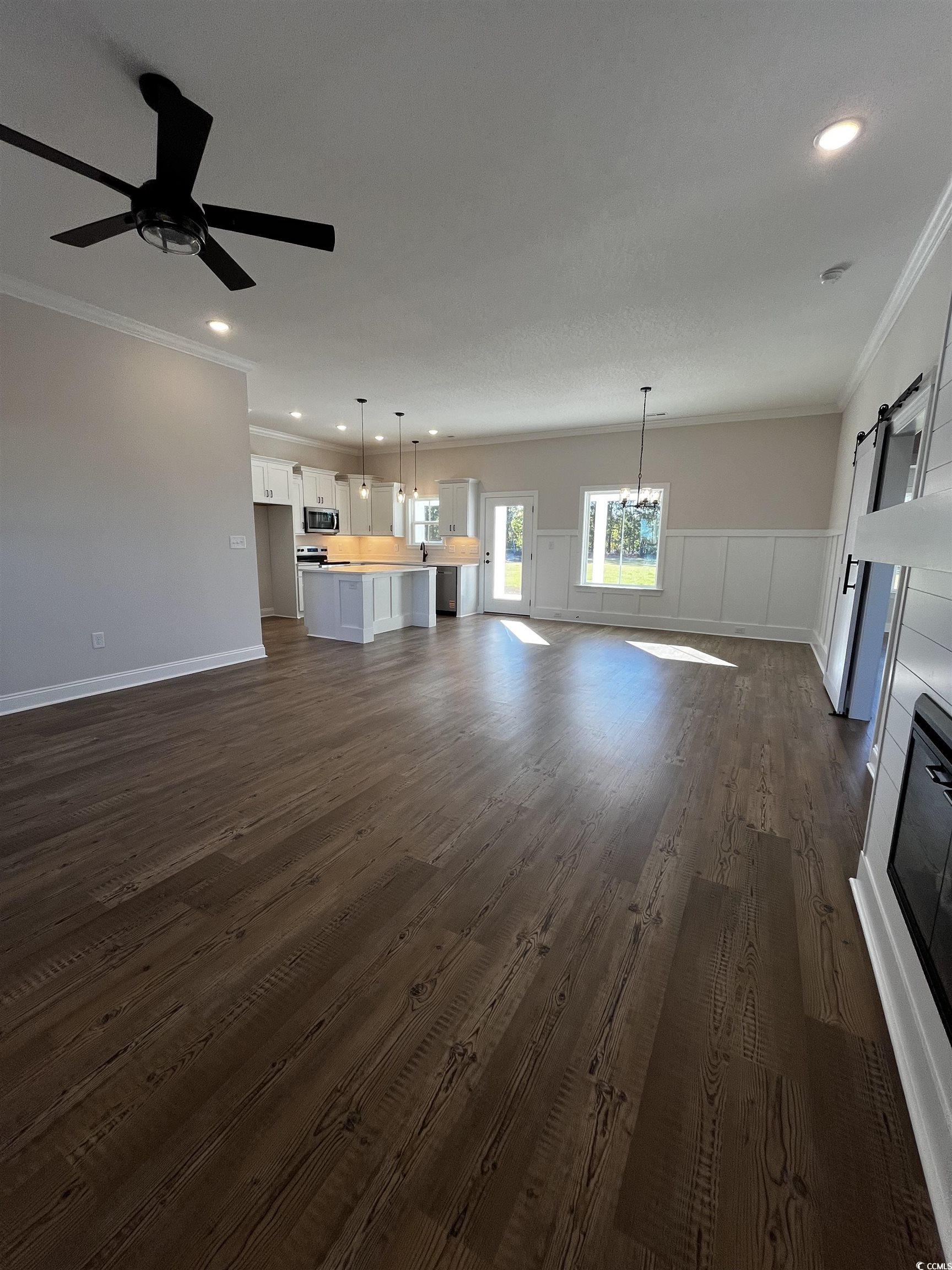 3428 Asbury Road Aynor, SC 29511 - Photo 2 of 10 Unfurnished living room with ornamental molding, dark wood-style flooring, recessed lighting, a barn door, and a ceiling fan