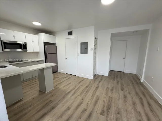 a view of kitchen with wooden floor and electronic appliances
