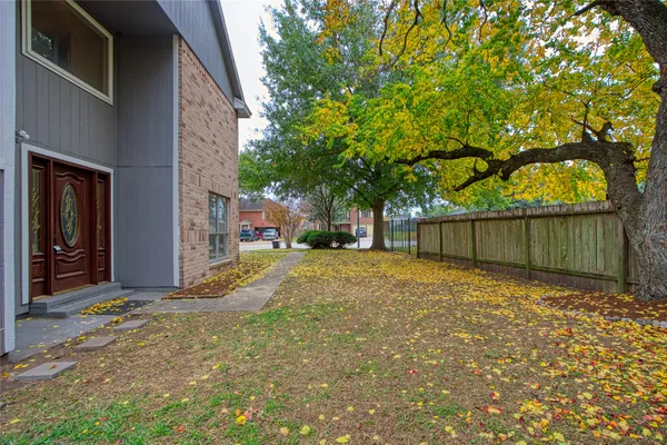 a backyard of a house with large trees and a wooden fence
