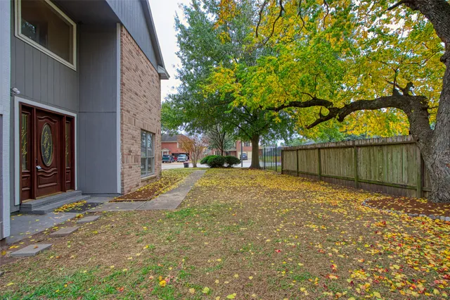 a backyard of a house with large trees and a wooden fence