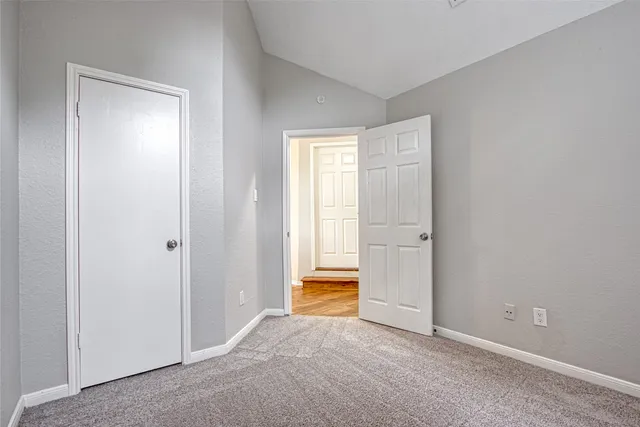 an empty room with wooden floor chandelier and windows