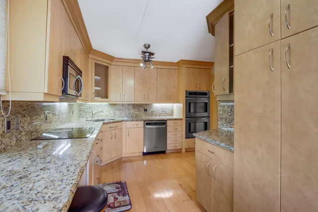 a kitchen with stainless steel appliances granite countertop a sink a stove and a refrigerator