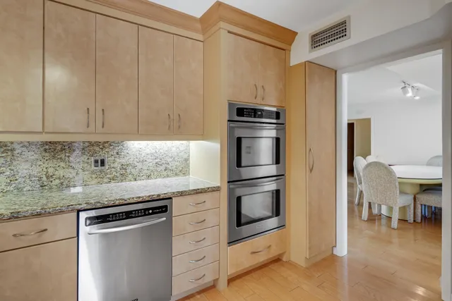 a kitchen with granite countertop a refrigerator stove and cabinets