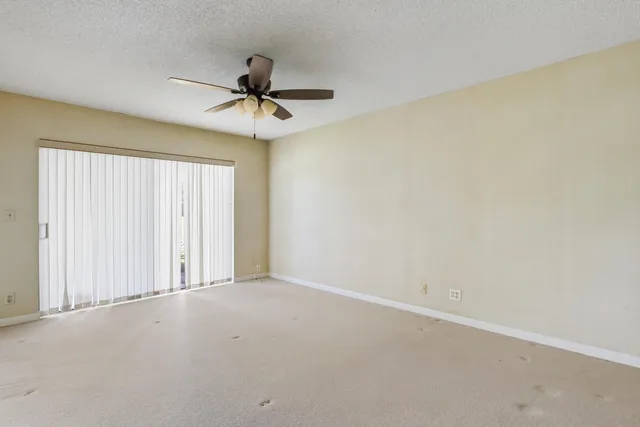 an empty room with a window and a fan