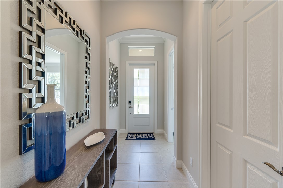 6145 Bella Rosa Lane Vero Beach, FL 32966 - Photo 2 of 8 a view of a hallway that has a dresser and a chandelier