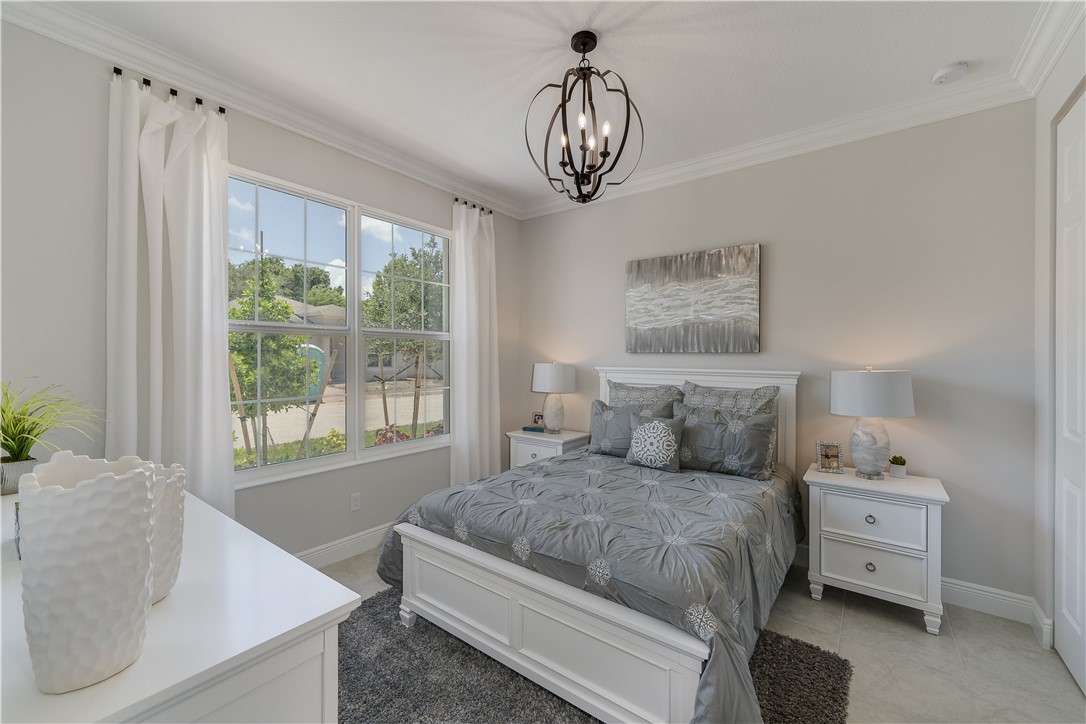 6145 Bella Rosa Lane Vero Beach, FL 32966 - Photo 3 of 8 a bedroom with a bed and a chandelier