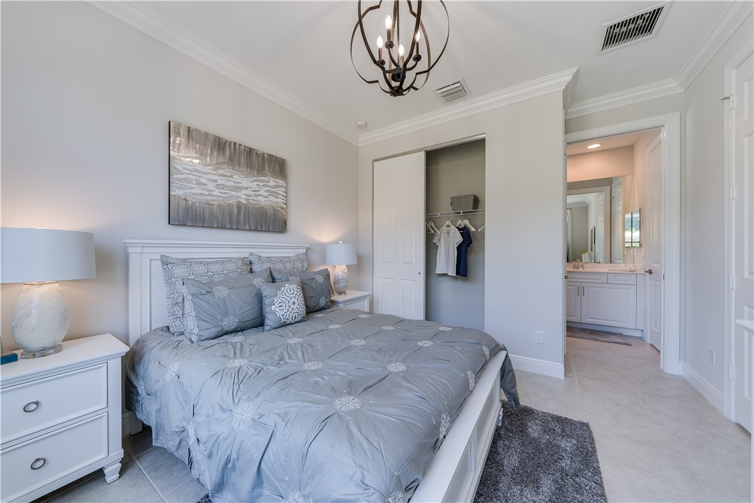 6145 Bella Rosa Lane Vero Beach, FL 32966 - Photo 4 of 8 a bedroom with a large bed and a chandelier