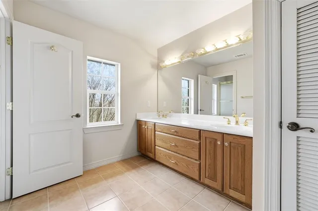 a spacious bathroom with a double vanity sink a mirror and a bathtub
