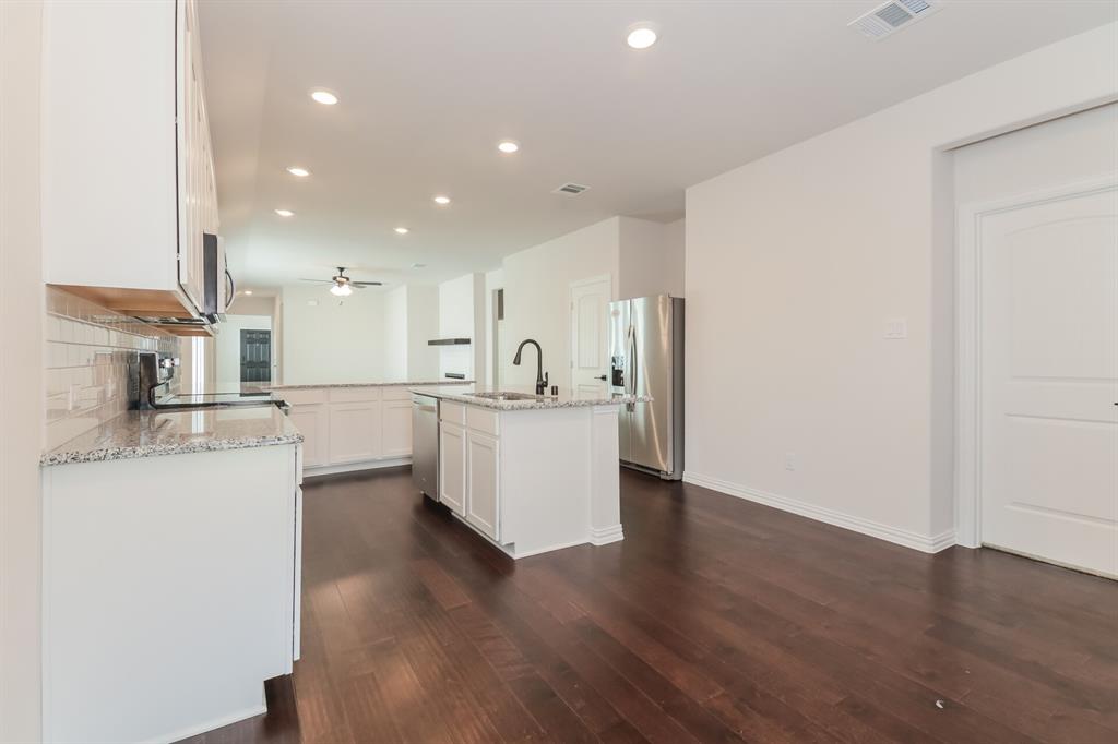 2610 Hawkins Street Anna, TX 75409 - Photo 7 of 17 Kitchen with recessed lighting, light stone counters, a kitchen island with sink, white cabinets, and appliances with stainless steel finishes