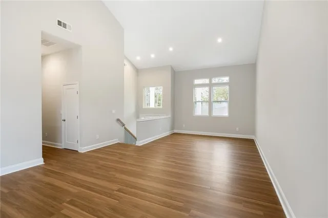 an empty room with wooden floor and windows