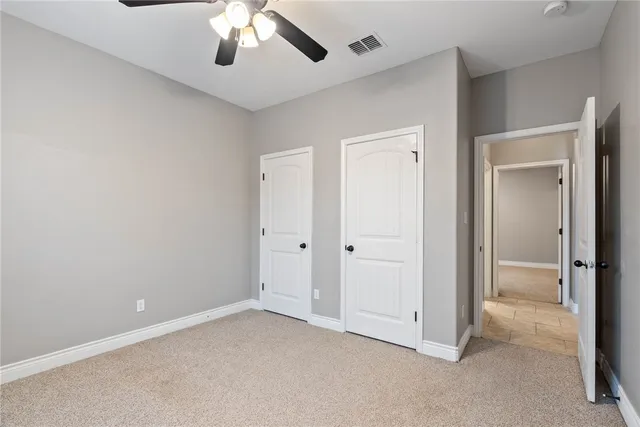 a view of an empty room and chandelier fan