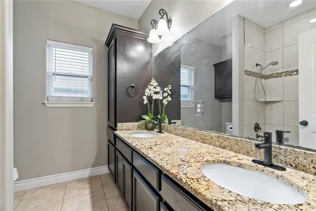 a bathroom with a granite countertop sink a large mirror and a shower