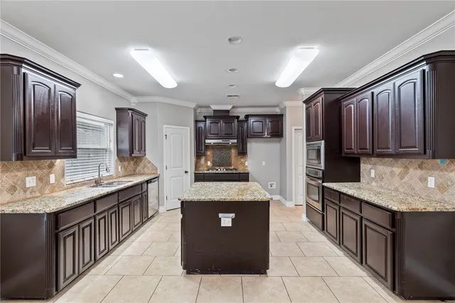 a kitchen with stainless steel appliances granite countertop wooden cabinets a counter top space and a sink