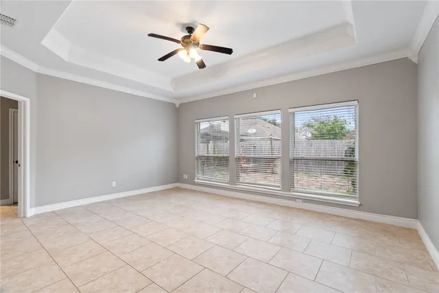 an empty room with chandelier fan and windows