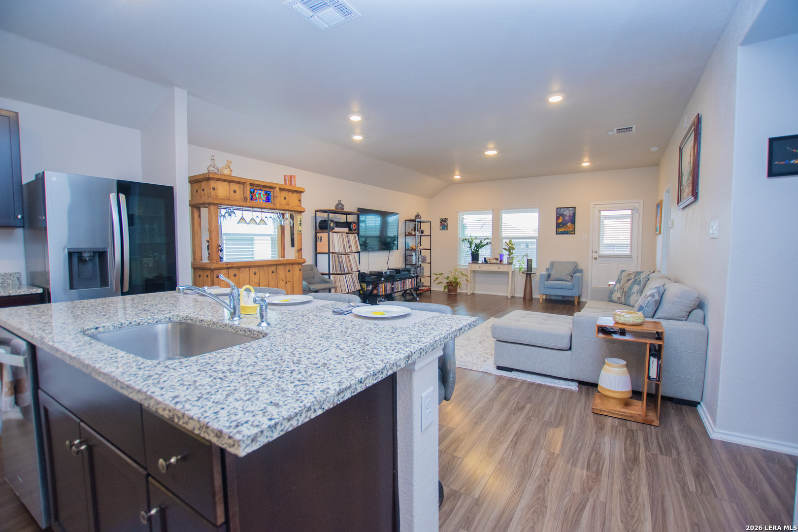 837 Indigo Way Seguin, TX 78155 - Photo 6 of 23 a kitchen island with granite countertop a sink and a wooden floors
