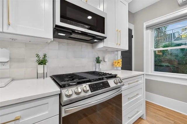 a kitchen with stainless steel appliances granite countertop a stove a sink and a microwave