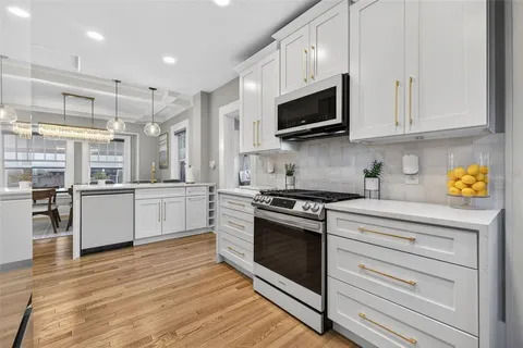 a kitchen with stainless steel appliances granite countertop a stove and white cabinets