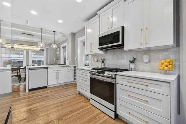 a kitchen with stainless steel appliances granite countertop a stove and white cabinets