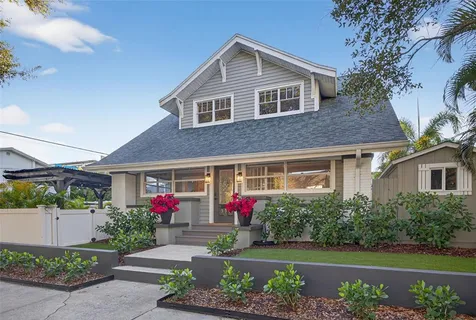 a front view of a house with a yard and potted plants