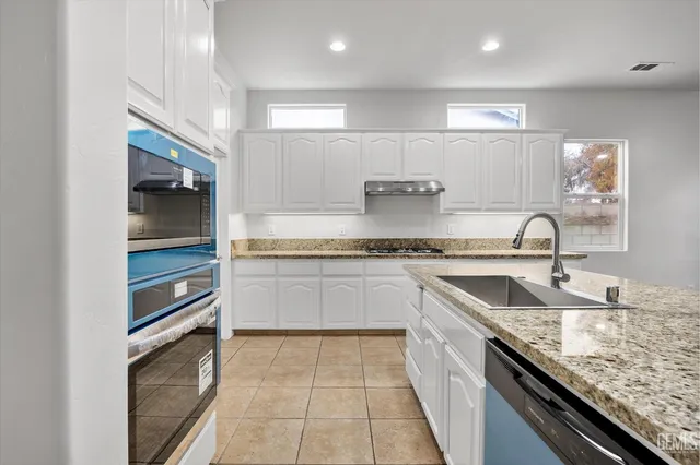 a kitchen with kitchen island granite countertop a sink and cabinets