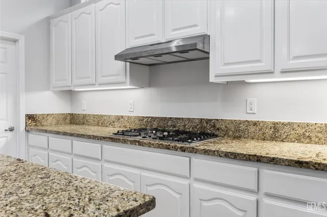 a kitchen with granite countertop white cabinets and stainless steel appliances