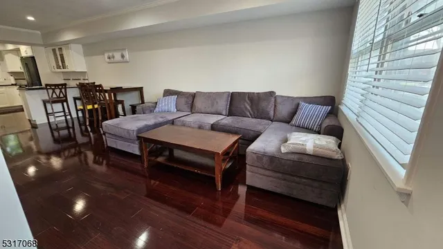 a living room with furniture a wooden floor and next to a window