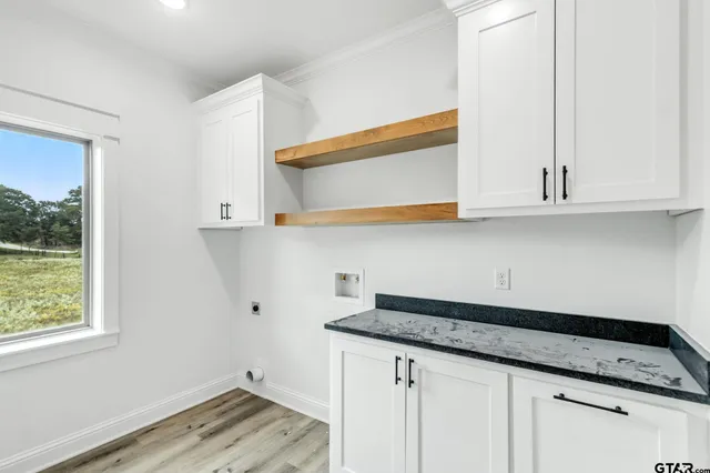 a kitchen with granite countertop white cabinets and a wooden floor