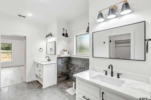a bathroom with a double vanity sink mirror and bathtub