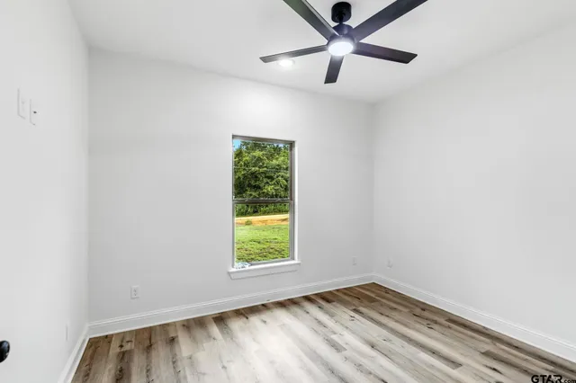 an empty room with a window and a ceiling fan