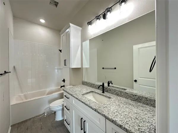 a bathroom with a granite countertop sink a toilet and bathtub