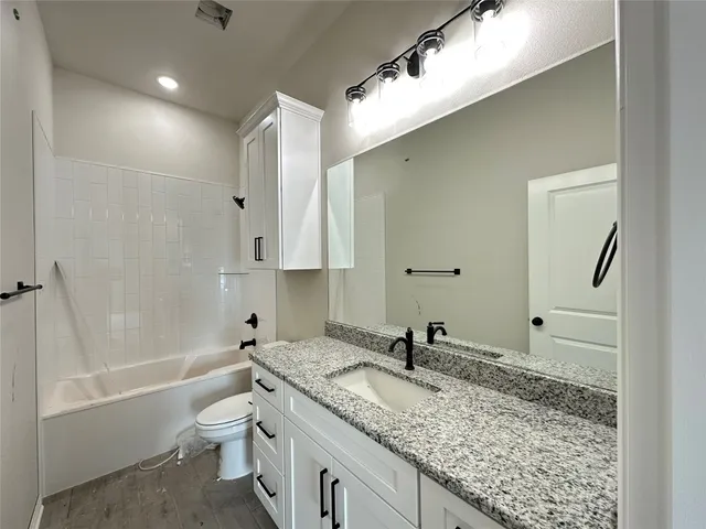 a bathroom with a granite countertop sink a toilet and bathtub