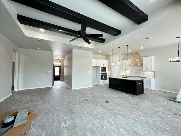 a view of an empty room with kitchen and kitchen view