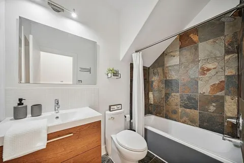 a bathroom with a bathtub shower sink vanity mirror and toilet